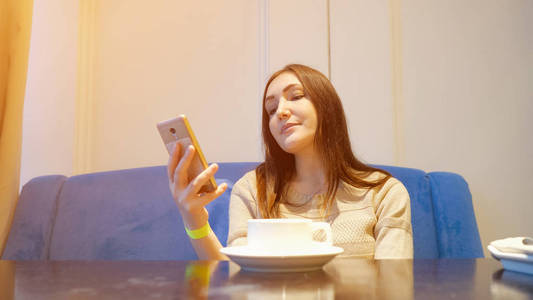 在咖啡馆喝咖啡，使用移动电话的年轻女子