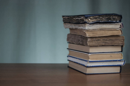 一叠书在一张棕色的木桌上，上面有铭文的空间。 旧书。 教育。