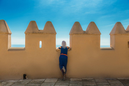 身穿蓝色衣服的妇女透过堡垒墙, 阿尔卡萨巴, 阿尔梅利亚, 西班牙