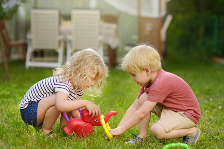 可爱的小男孩和女孩在夏天户外玩投掷戒指的游戏。夏季户外有孩子的家庭运动会。