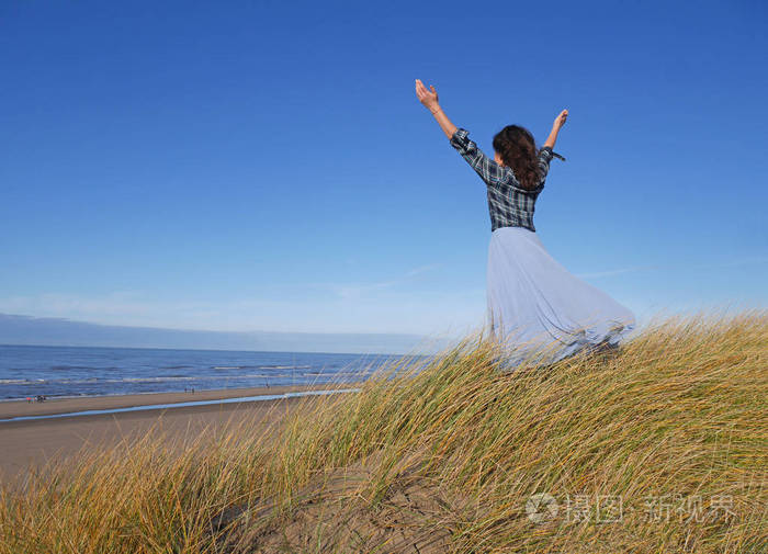 女孩站在海边靠在天空和双手