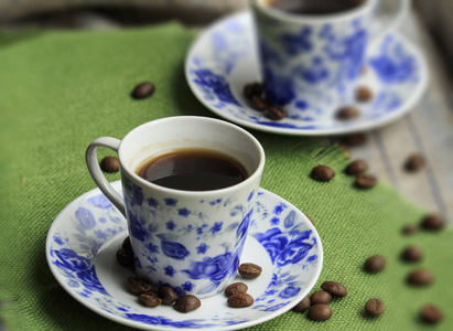 一杯咖啡和咖啡种子放在蓝玫瑰盘子里