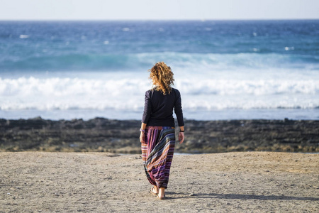 一位女士在海滩上漫步到海浪中，享受自由和自然