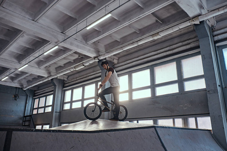 带着 bmx 的年轻人准备在室内的滑板公园里跳来跳去