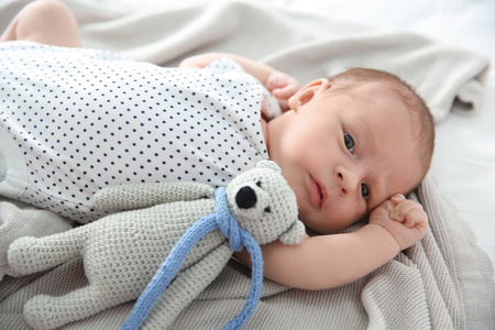 可爱的新生婴儿，玩具熊躺在柔软的毯子上