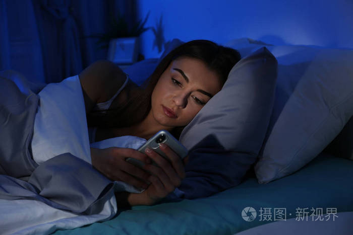 晚上带手机的年轻女人睡觉