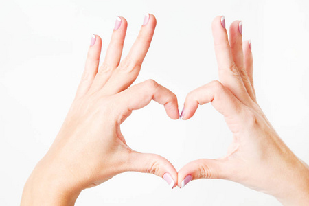 女人用手指形成心脏征。 双手孤立在白色背景上。 水平彩色摄影。