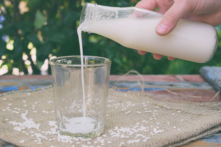 大米牛奶与米粒一起装在瓶子里。 替代类型的牛奶。 纯素非牛奶。 无乳糖牛奶和非奶饮料。 乳糖不耐受症。 健康的食物。