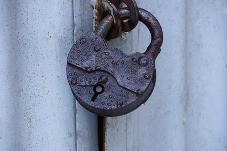 一个棕色的大挂锁，挂在灰色的金属门上