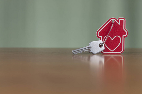 房屋钥匙在房子上，形状的钥匙链，放在木桌上，用于房地产搬迁或租赁财产的概念