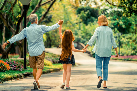 夏天，幸福健康的家庭一起在公园的小路上散步。 家庭结合的概念。