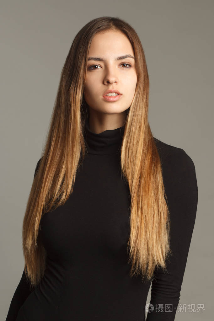 摄影棚肖像,年轻漂亮的女人,留着长长的漂亮头发在灰色背景上