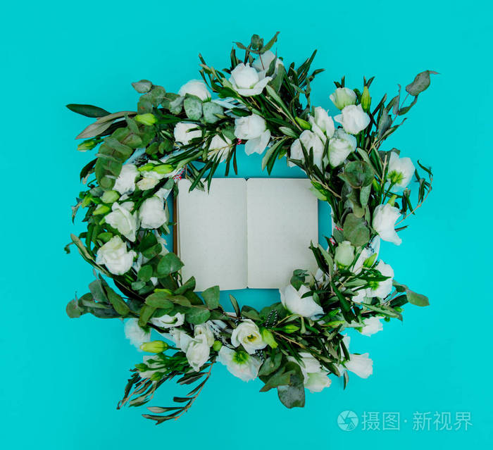 绿松石背景下花圈和食谱笔记本的装饰组成.