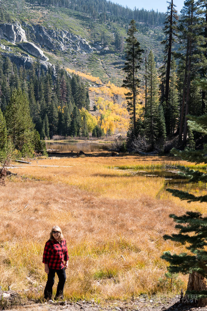秋天,金发女性中年徒步旅行者在索彻湖摆姿势,树叶上有秋天的颜色.