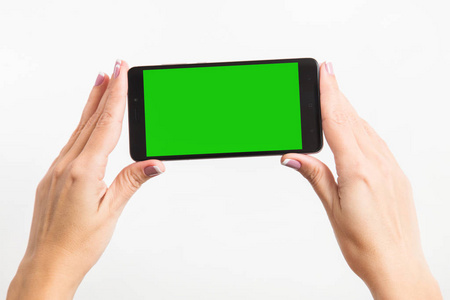 s two hands holding black mobile phone with blank green screen i