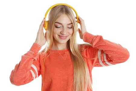 带着耳机在彩色背景下听音乐的漂亮年轻女人