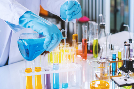 具有设备和科学实验的科学家，实验室玻璃器皿中含有化学液体，用于在实验室中研究或分析样品到试管中。