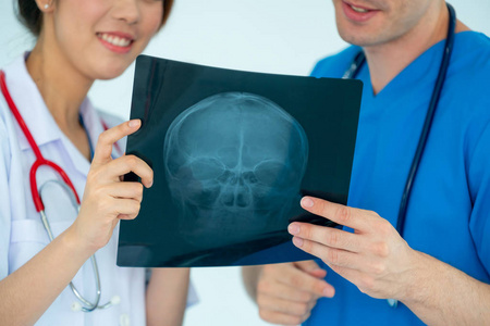 女医生在医院与另一位医生一起工作时，看了病人头部损伤的X光片。 医疗保健人员和医生服务。