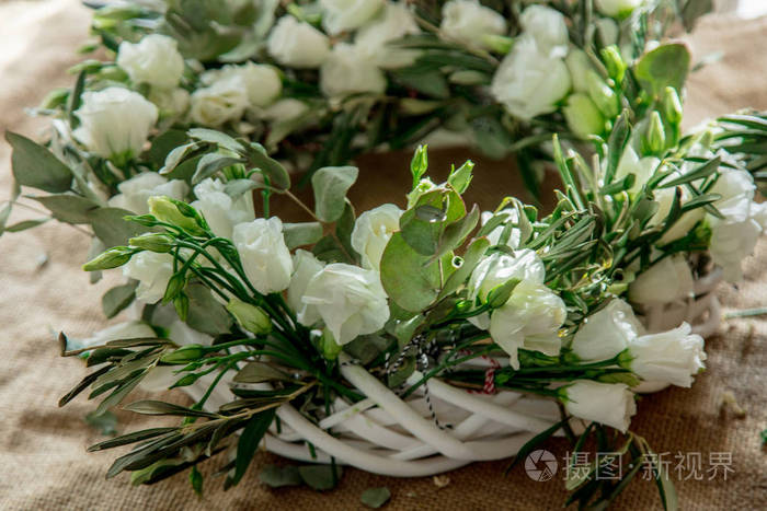 用麻布背景上的白玫瑰和白玫瑰制成的花环。
