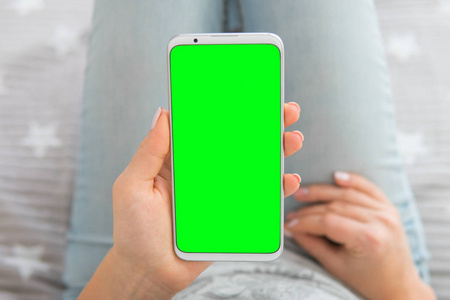 女人手拿着手机的模拟图像。绿色屏幕智能手机。色度键。顶视图