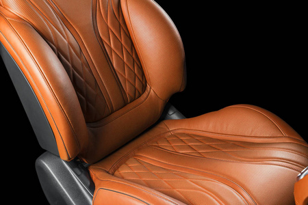 豪华现代汽车的棕色皮革内饰。 穿孔橙色皮革舒适座椅与缝纫隔离在黑色背景。 现代汽车内饰细节。 汽车细节。 汽车里面