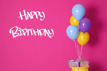 一群明亮的气球，礼物和短信，生日快乐，靠近粉红色的墙