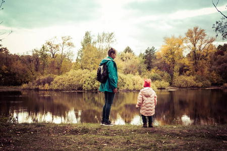 秋天，妈妈和女儿在森林湖的岸边