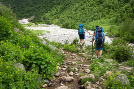 在山里徒步。游客与背包穿越山河。在荒山徒步旅行