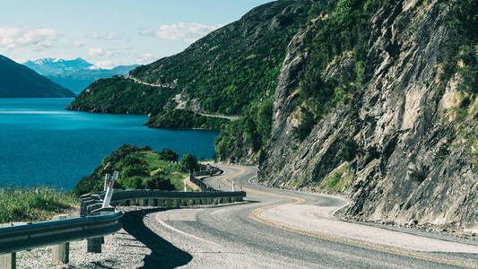 新西兰南岛皇后镇沿山崖和湖泊景观蜿蜒曲折的道路。 夏天的旅行和公路旅行。