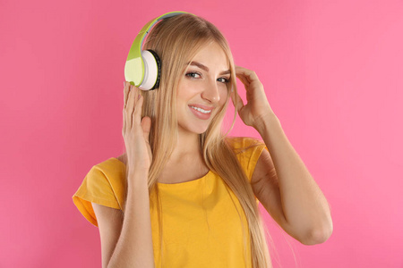 带着耳机在彩色背景下听音乐的漂亮年轻女人
