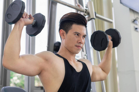 肌肉男健美运动员在健身健身房训练哑铃.
