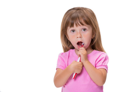 特写肖像可爱的小女孩3岁，穿着粉红色的t恤刷牙，孤立在白色背景上。