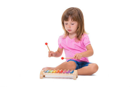 可爱的微笑，开朗，积极的女孩，3岁，玩乐器玩具木琴，孤立在白色背景上。