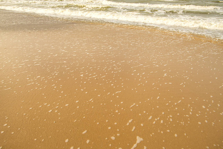 海浪的泡沫泡在沙滩上