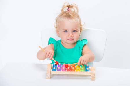 可爱的微笑的孩子，小金发女孩玩音乐玩具木琴孤立在白色背景。