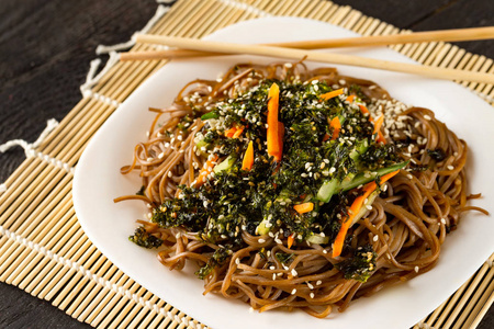 与简单的蔬菜沙拉特写荞麦面与蔬菜沙拉与筷子在木桌背景.照片