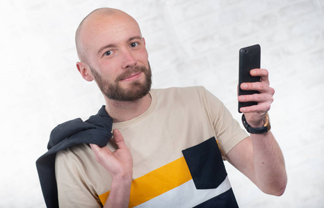 一个留着胡子的年轻人，用黑色智能手机说话