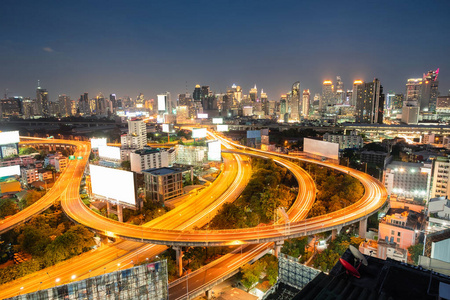 鸟瞰交通在曼谷的高架道路上发光，有摩天大楼