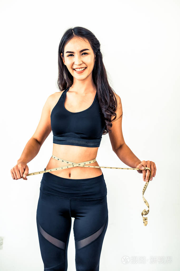 近距离拍摄的妇女与苗条的身体测量她的腰围和躯干.