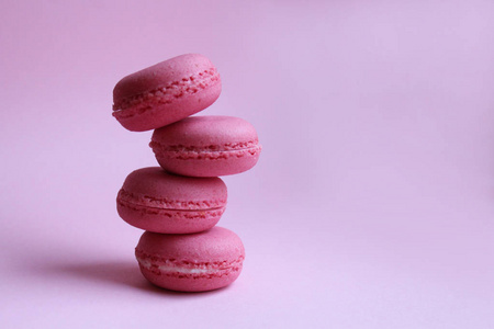 浅粉色背景下的四个粉红色马卡龙，最低食品概念
