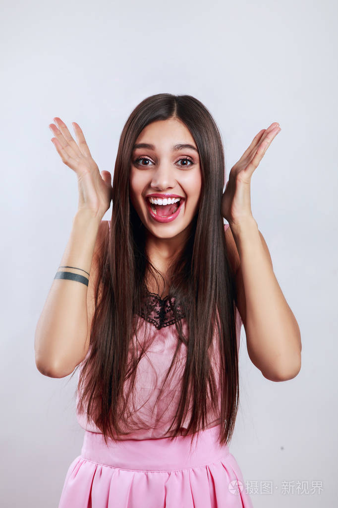 美丽的黑发女人惊喜显示产品.展示您的产品.在灰色背景上隔离.