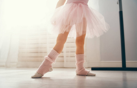可爱的小女孩梦想成为芭蕾舞演员。穿着粉红色芭蕾舞裙的小女孩在房间里跳舞。小女孩正在学习芭蕾。
