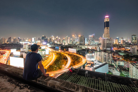 男人坐在阳台上观光,城市在夜晚发光照片