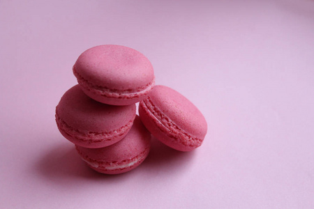 浅粉色背景下的四个粉红色杏仁饼，最小的食物概念