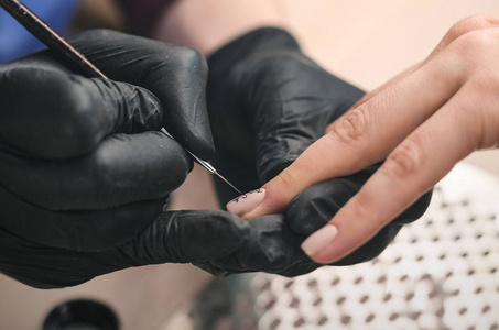 s nails with a gel polish in a beauty salon, close up.