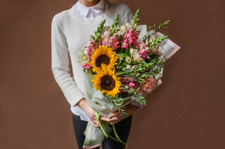 女人手里拿着一束漂亮的花。 3月8日妇女日。 向日葵康乃馨阿斯特龙亚桉树抗rrrinum。 为假期做准备