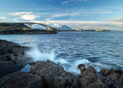 挪威大西洋大道旁的岩石海岸。 长曝光镜头。 在著名的斯托西桑德布鲁阿桥和破浪。
