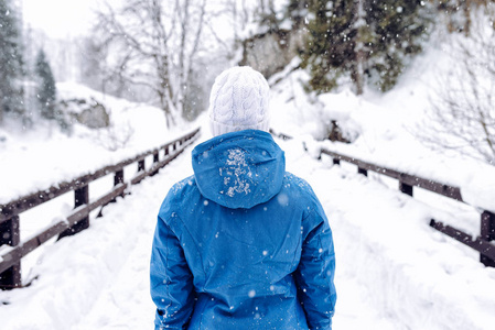 冬天穿暖和夹克的女人，在雪山上散步的白色羊毛帽
