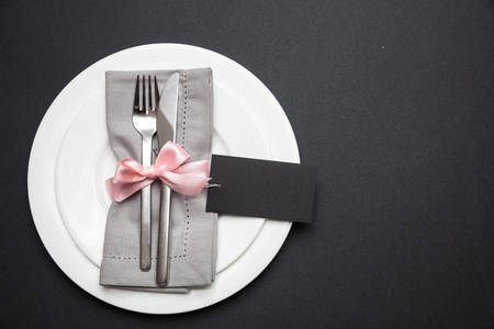 桌子位置设置亚麻餐巾，粉红色丝带，空白标签，黑色背景，顶部视图，复制空间。