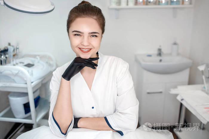 积极漂亮的年轻美容师坐在房间里在镜头前摆姿势她笑了美容师牵手后